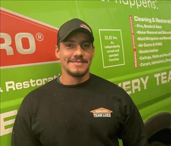 Male with a baseball cap with SERVPRO Merchandise on standing in front of a green SERVPRO van