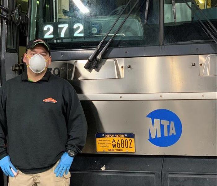 SERVPRO owner with face mask, gloves and other PPD in front of bus