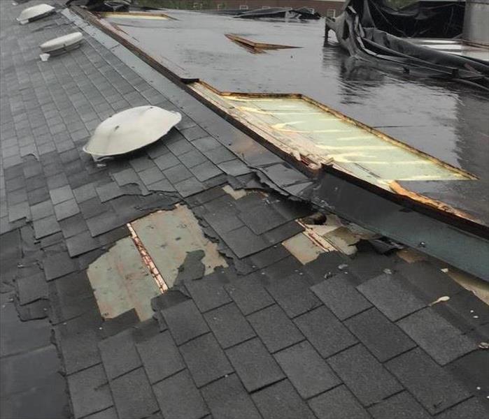 A roof on top of one of the buildings at UNCW, singles are missing and exposed wood is damaged.