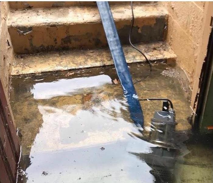 submersible pump inside a basement doorway with the blue hose