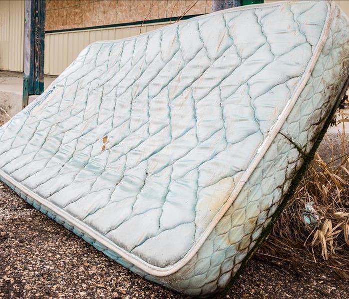A wet mattress on the side of the road